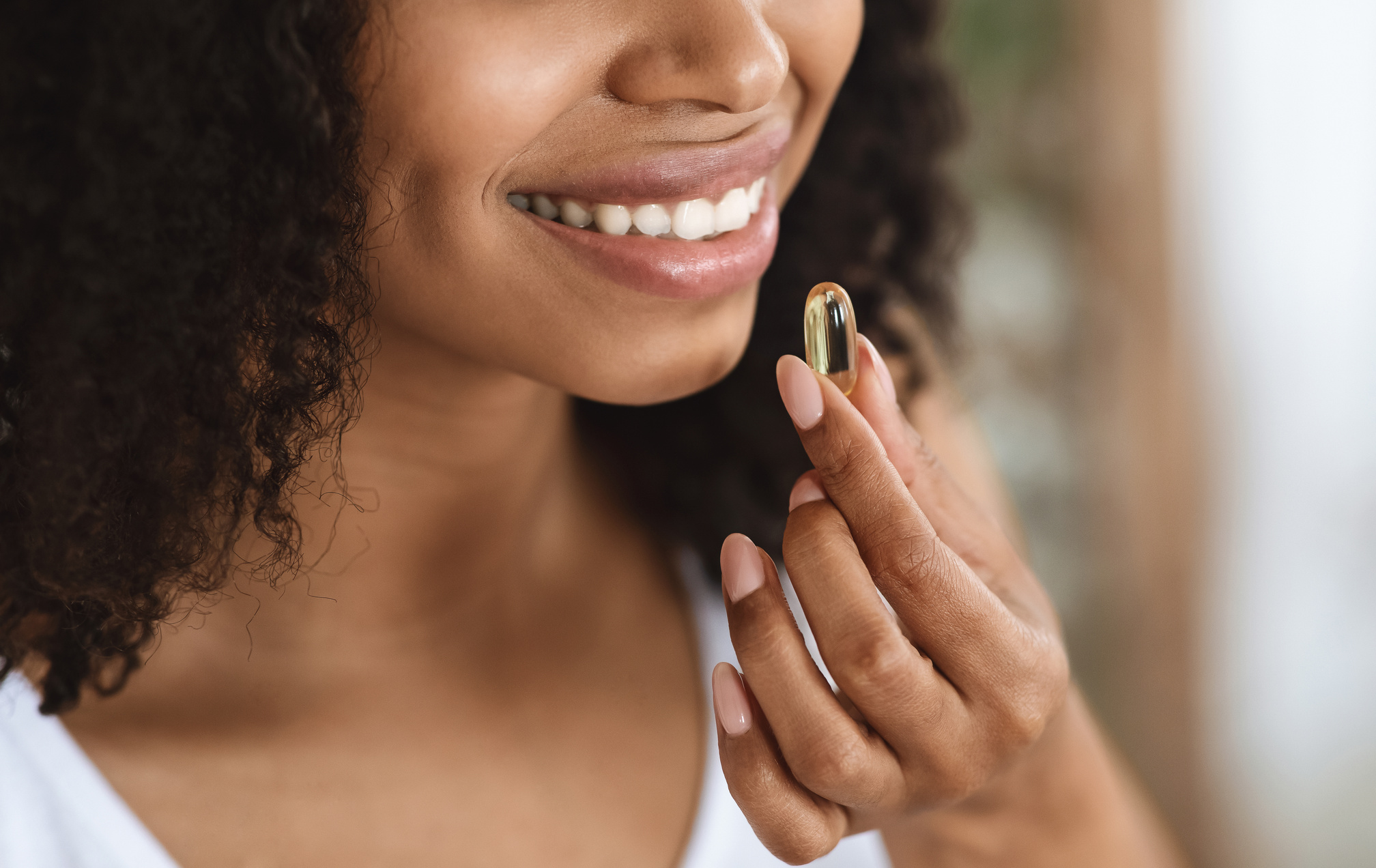 Beauty Supplement. Closeup Of Smiling Black Woman Taking Vitamin Pill Capsule